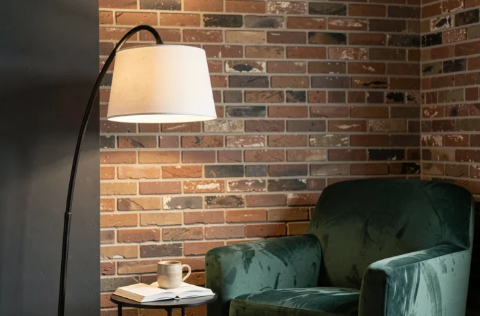 Lampadaire arc noir en métal au-dessus d'un fauteuil en velours vert dans un coin lecture cosy